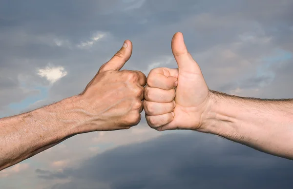 Zwei Männer stoßen Fäuste mit Daumen in den Himmel mit Wolken — Stockfoto