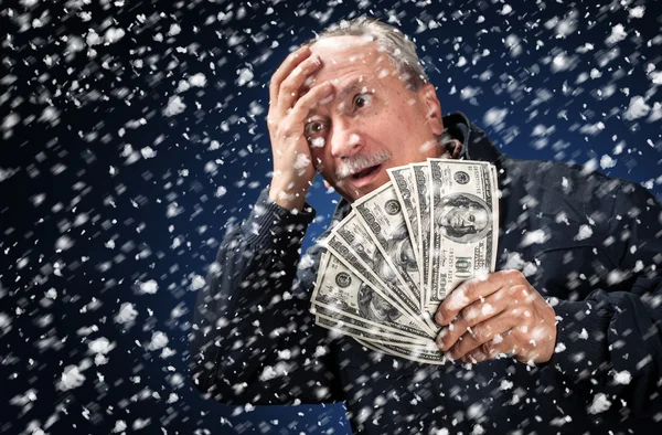 Человек с пачкой долларов в снегопаде — стоковое фото