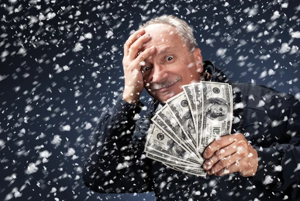 Человек с пачкой долларов в снегопаде — стоковое фото