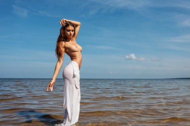 Deniz kenarında güzel genç çıplak kadın