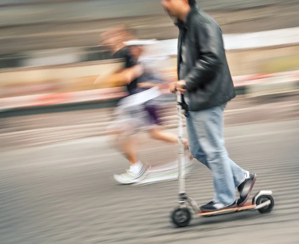 Mann auf Motorroller und Paar laufen die Straße hinunter — Stockfoto