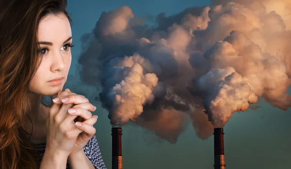 Mulher orante contra de tubos que poluem uma atmosfera — Fotografia de Stock