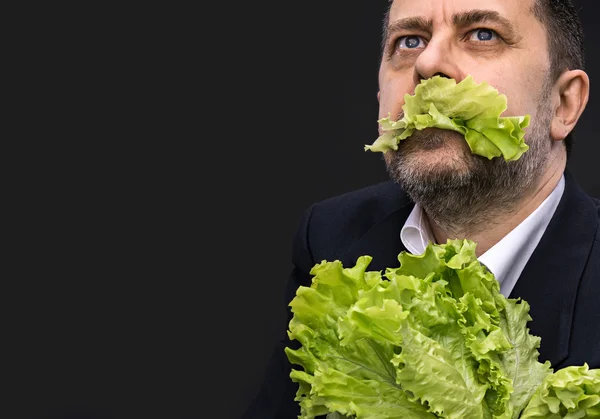 Uomo che tiene e mangia lattuga — Foto Stock