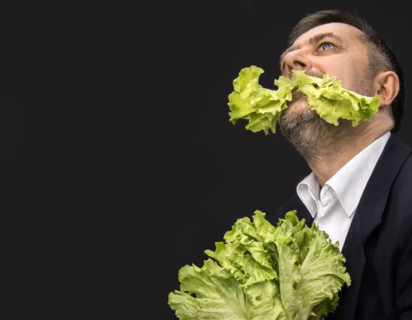 Hombre sosteniendo y comiendo lechuga — Foto de Stock