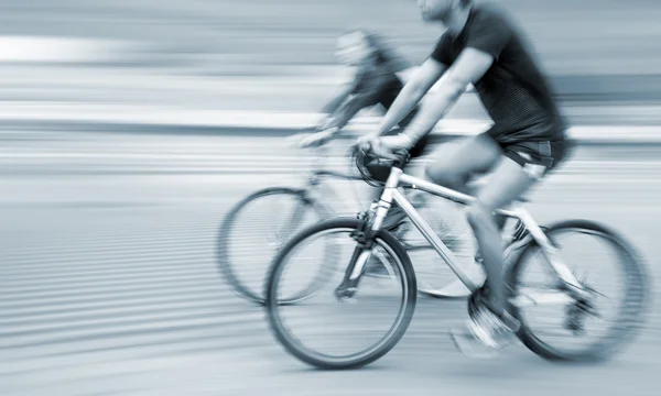 Young man and woman riding bicycles on a city street — Stock Photo, Image