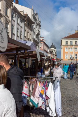 Lviv, Ukrayna - 12 Ekim 2025: Lviv 'deki Pazar Meydanı, ziyaretçiler fuarı keşfederken, yerel el sanatları ve açık mavi gökyüzü altındaki yiyeceklerle dolup taşıyor.