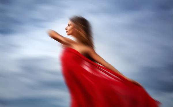 Femme floue sur une plage avec un tissu rouge — Photo