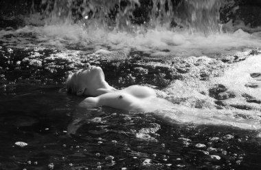 Huzurlu siyah beyaz bir fotoğrafta çıplak poz veren genç bir kadın, sükunet anında yakalanır.