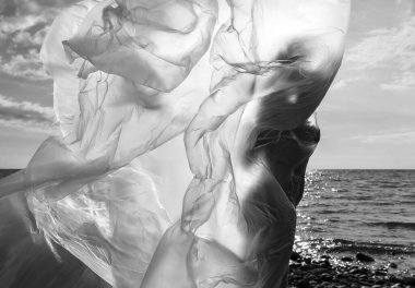 Rüzgarlı deniz sahilinde, plastik ambalajın arkasında güzel, çıplak bir kadın. Polietilen film altında sanatsal vücut portresi, doğa arka planı. Kavramsal açık hava fotoğrafı.