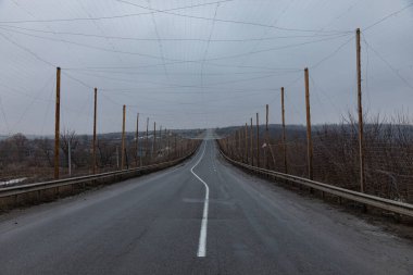 Harkiv bölgesinde asfaltlı bir yolun üzerinde geniş bir anti-drone ağı asılı görülüyor. Ahşap direkler, koruyucu ağ ızgarasını desteklemek için asfaltı dizerken görülüyor..