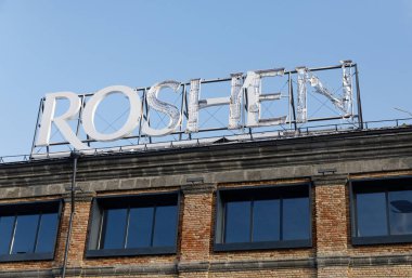 KYIV, UKRAINE - 24 Ocak 2026: Hasarlı bir Roshen fabrika tabelası Kyiv 'de bir İHA saldırısının ardından tuğla bir binanın tepesinde duruyor. Çarpık metal harfler saldırının etkisini gösteriyor..