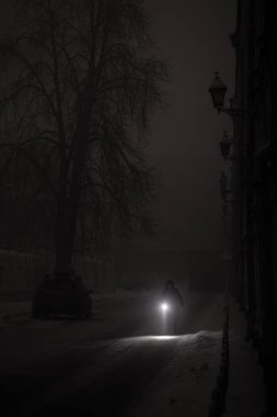 Bir Kyiv sakini, ciddi bir elektrik kesintisi sırasında el feneriyle ışıksız bir caddede geziniyor. Dondurucu sıcaklıklar hasar gören şebekeyi zorlarken acil durum kesintileri başkenti karartıyor.