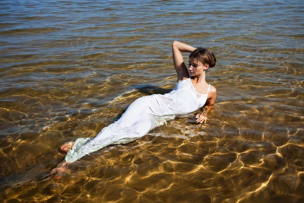 Mädchen in weißem Kleid liegen im Wasser — Stockfoto