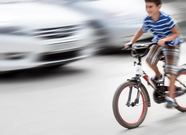 Dangerous city traffic situation with a boy on bicycle — Stock Photo, Image