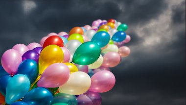 Multi-colored balloons on dark dramatic sky