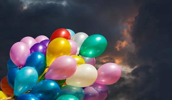 Multi-colored balloons on dark dramatic sky — Stockfoto