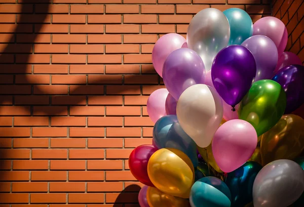 Multi-colored balloons on brick wall background — Stok fotoğraf
