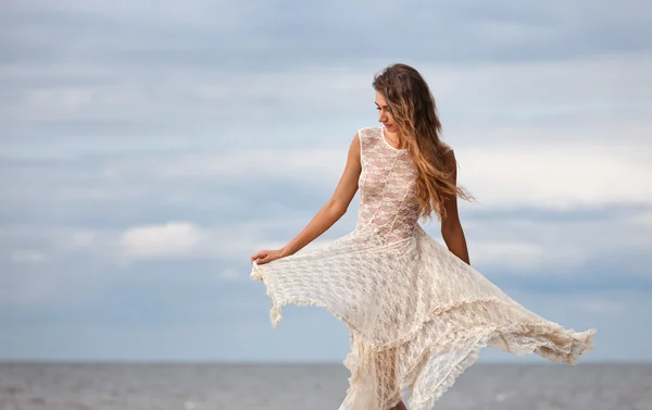 Flicka i en halvtransparent klänning mot havet — Stockfoto