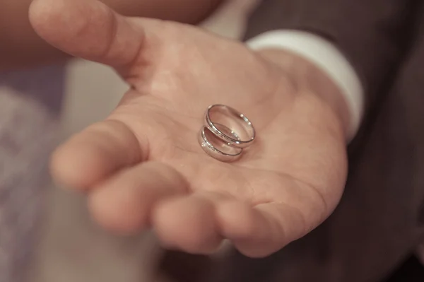 Noivo segurando anéis de casamento dourados a mãos — Fotografia de Stock