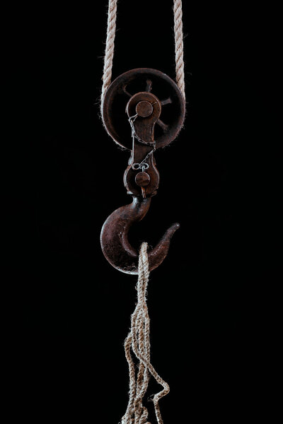 Большой металлический крючок висит на веревке
