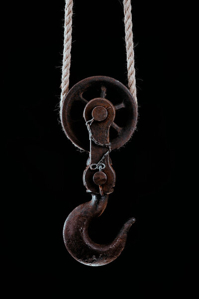 Большой металлический крючок висит на веревке

