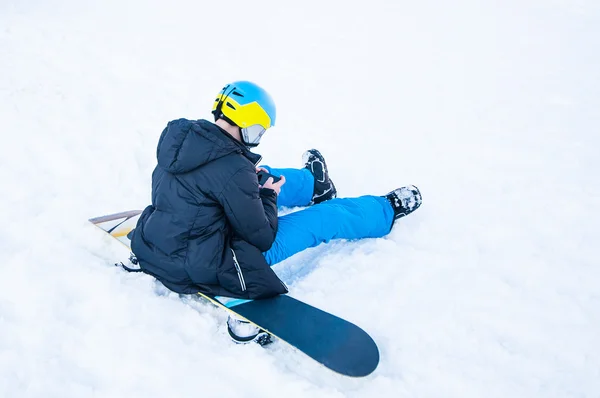 Snowboardzista siedzi na tle śniegu — Zdjęcie stockowe