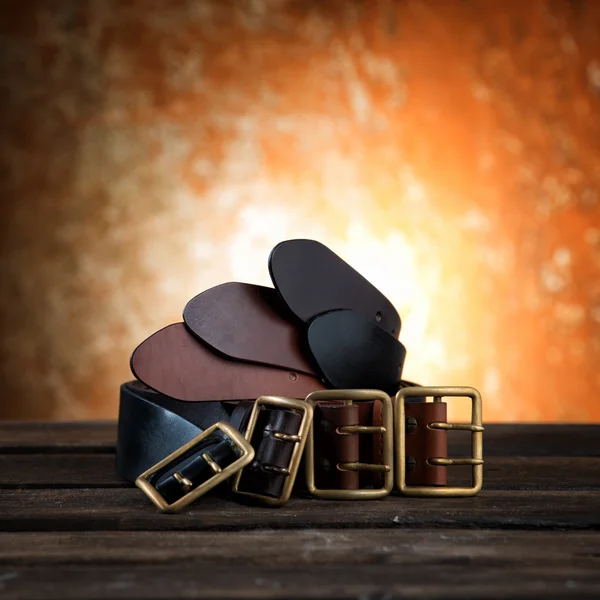 Different belts with buckle on rusty wooden background — Stock Photo, Image