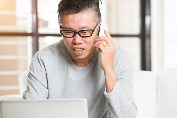 Azjatycki człowiek przy użyciu telefonu i laptopa — Zdjęcie stockowe