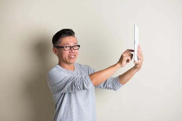 Mognade asiatiska man använder tablet — Stockfoto