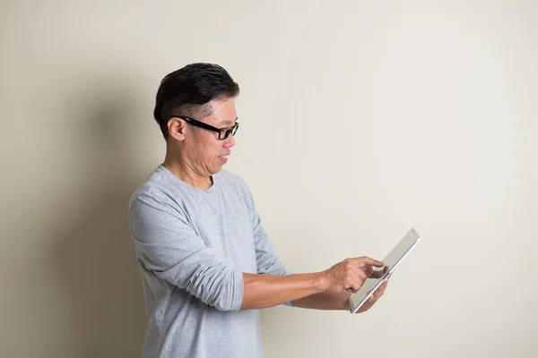 Зрелый азиатский человек с помощью планшета — стоковое фото