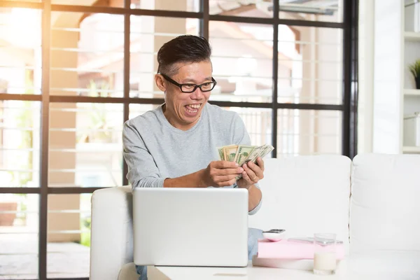 Homem sênior feliz com dinheiro e laptop — Fotografia de Stock
