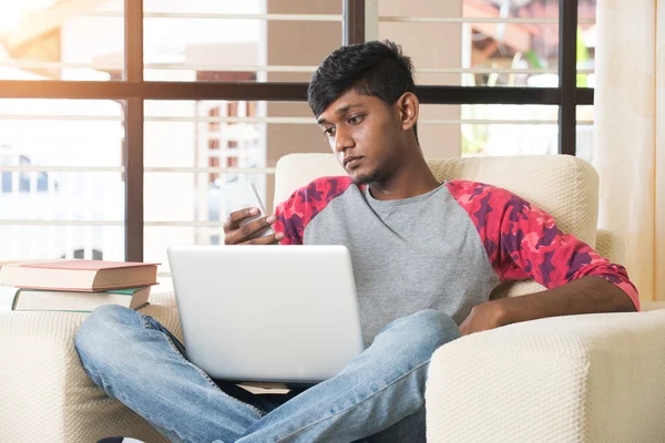 Ragazzo indiano utilizzando laptop e telefono — Foto Stock