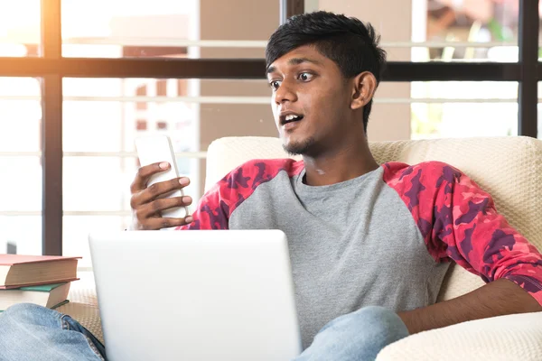 Підліток індійський хлопчик з ноутбуком і телефоном — стокове фото