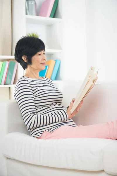 Asian matured senior woman reading on a sofa — Stock Photo, Image