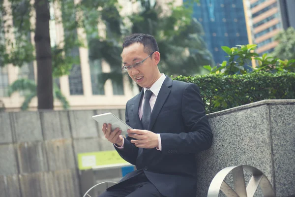 Aziatische business man met behulp van draagbare computer op park in hong kong — Stockfoto