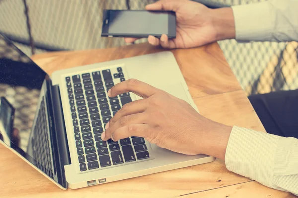 Hombre de negocios asiático con teléfono inteligente y portátil — Foto de Stock