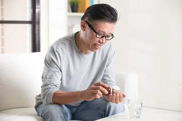 Asian senior male taking pills — Stock Photo, Image