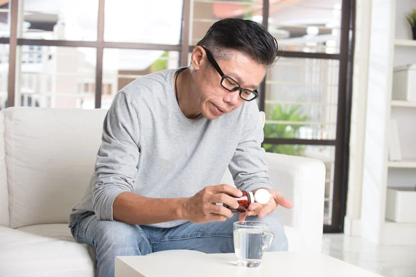 Asian senior man taking pills — Stock Photo, Image