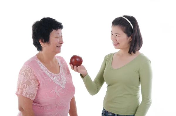 Senior woman with daughter having apple — ストック写真