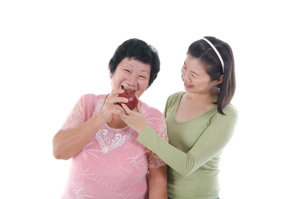 Senior woman with daughter having apple — Stock Photo, Image