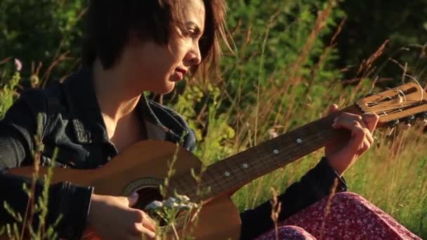 Glückliches junges Mädchen, das draußen Gitarre spielt. — Stockvideo