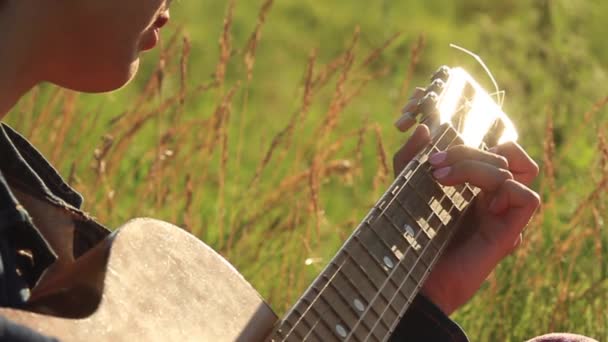 Щаслива молода дівчина грає на гітарі на відкритому повітрі . — стокове відео