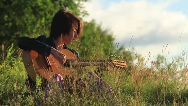 Chica joven feliz tocando la guitarra al aire libre . — Vídeos de Stock