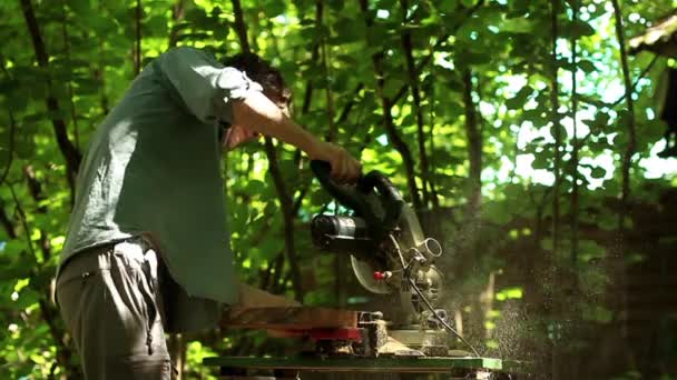 Carpinteiro trabalhando com ferramenta industrial na fábrica de madeira, lâmina circular com uma placa de madeira — Vídeo de Stock