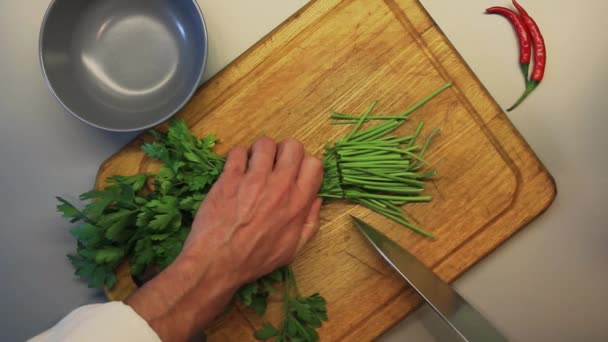 Кухар нарізає петрушку на дошці — стокове відео