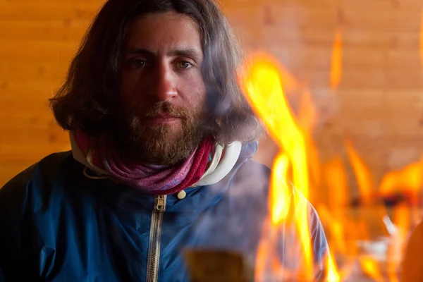 Um homem com cabelo comprido perto de um fogo — Fotografia de Stock