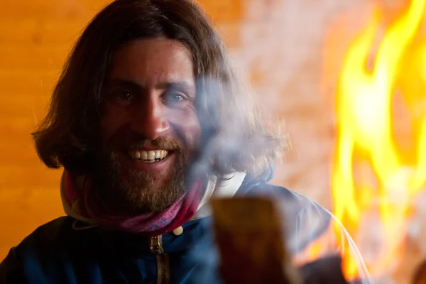 Un hombre con el pelo largo cerca de un fuego —  Fotos de Stock