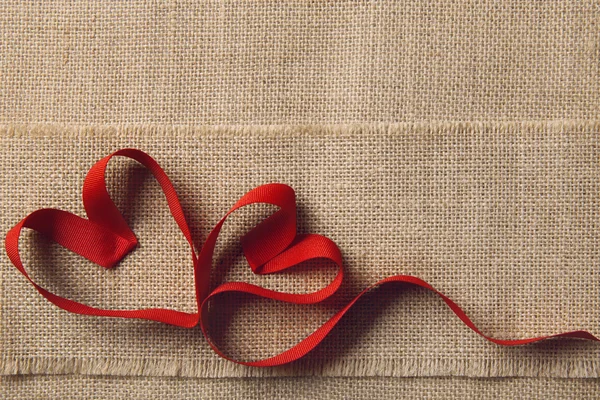 Dos corazones en fondo de arpillera de saco. Concepto de amor de San Valentín o boda. Forma de cinta como pareja unida —  Fotos de Stock