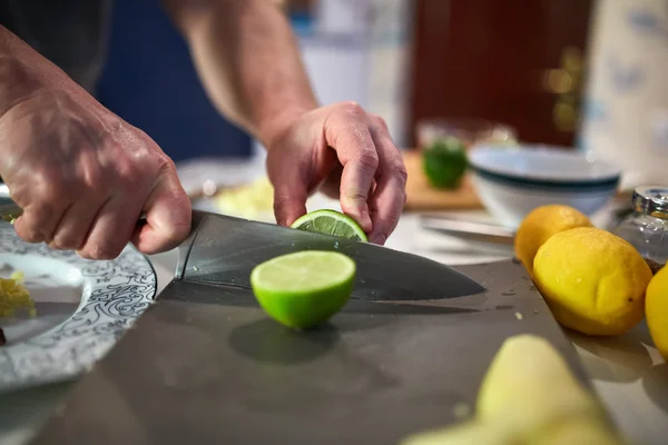 Hænder af mand skære limefrugter - Stock-foto