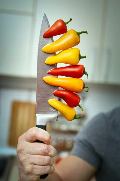 Manteniendo pimientos en un cuchillo — Foto de Stock